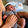 baby, infant, striped_onesie, adult_hand, beard, couch, pillow, smile, relaxing, indoor, person, skin, foot, hand, comfort, parent, child, home, rest, happy