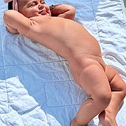 Alegria a rejoint le concours — aidez-le/la à gagner de superbes lots ! baby, child, barefoot, headband, bracelet, smiling, relaxed, skin, lying_down, quilt, white, sunlight, cheeky, happy, infant, cute, outdoor, portrait, person, toddler