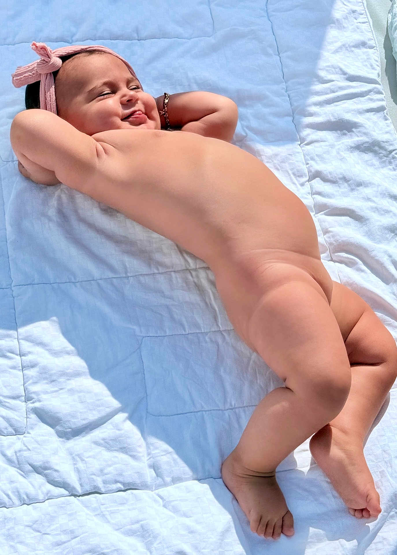 Alegria a rejoint le concours — aidez-le/la à gagner de superbes lots ! baby, child, barefoot, headband, bracelet, smiling, relaxed, skin, lying_down, quilt, white, sunlight, cheeky, happy, infant, cute, outdoor, portrait, person, toddler