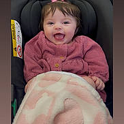 Freyja is registered to the contest to win money with this photo: baby, child, smile, pink_bow, pink_sweater, blanket, car_seat, happy, infant, cute, face, portrait, indoors, clothing, person, cozy, blanket_pattern, head, sitting, baby_girl
