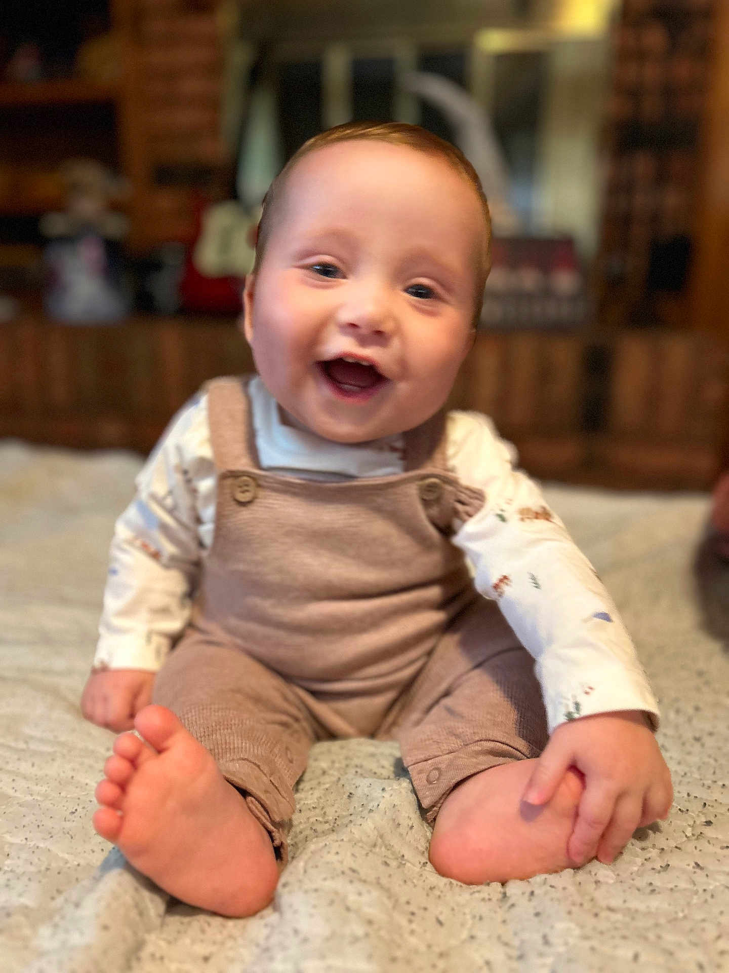 Remington is registered to the contest to win money with this photo: baby, child, smiling, sitting, feet, hand, clothing, onesie, bed, blanket, indoor, cute, happy, portrait, infant, face, skin, person, young, cozy