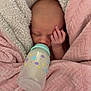 baby, newborn, bottle, blanket, pink_blanket, cream_blanket, sleeping, face, hand, infant, cozy, cute, peaceful, wrapped, nursery, soft_texture, feeding, child, person, indoors
