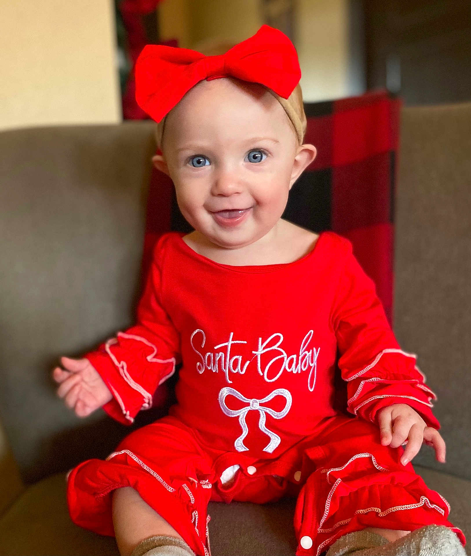 Novelynn joined the competition — help win amazing prizes! baby, child, smiling, red_outfit, headband, red_bow, sitting, chair, plaid_blanket, indoors, cute, happy, portrait, festive, holiday_theme, person, infant, clothing, face, hands