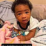 baby, child, infant, portrait, sitting, lying_down, curious, face, eyes, hair, smiling, indoors, bed, blanket, plush_toy, clothing, bottle, home, photograph, text_overlay