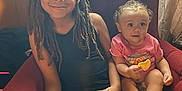 Kaelee joined the competition — help win amazing prizes! child, baby, smile, armchair, indoor, curtains, wood_paneling, shorts, tshirt, snack, relaxing, sitting, happy, dreadlocks, curly_hair, barefoot, furniture, family, cozy, home