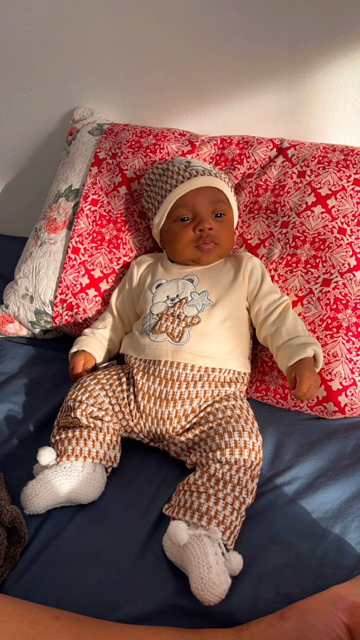 Mamady a rejoint le concours — aidez-le/la à gagner de superbes lots ! baby, baby_toddler_clothing, bedding, comfort, couch, eye, hat, head, headwear, human_leg, knee, linens, pattern, person, pillow, room, sleeve, sock, t_shirt, textile