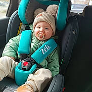 Yaël participe au concours pour gagner de l'argent avec cette photo : baby, beanie_hat, boots, car_interior, car_seat, child, cute, infant, jacket, pacifier, parking_lot, pom_poms, portrait, safety_harness, seat_belt, smiling, teal, toddler, window, winter_clothes