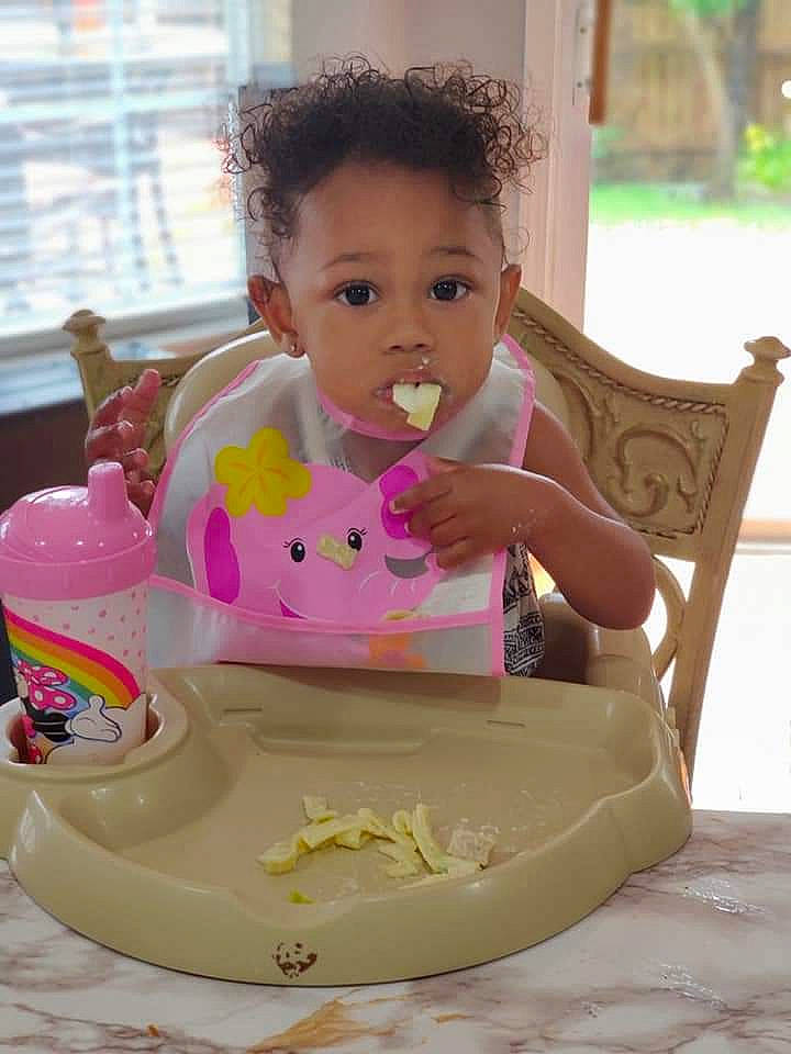 Denver is registered to the contest to win money with this photo: baby, baby_toddler_clothing, bib, chair, cheek, child, dishware, dress, drinkware, fun, happy, leisure, person, pink, serveware, sitting, skin, sweetness, tableware, toddler