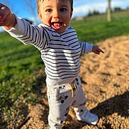 Aaron participe au concours pour gagner de l'argent avec cette photo : child, toddler, smiling, striped_shirt, sneakers, pants, outdoor, park, grass, blue_sky, sunlight, portrait, closeup, candid, happy, reaching, playground_surface, bokeh, expression, daytime