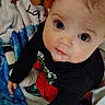 baby, child, infant, blanket, blue, stars, clothing, face, eyes, indoors, looking_up, person, cute, soft, young, sitting, curious, black_shirt, red_pants, home