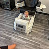 baby, child, infant, sitting, chair, salon_chair, white_chair, black_leather, indoor, floor, wood_floor, drink_fridge, beverages, home_interior, curious, blond_hair, face, portrait, furniture, photograph