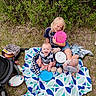 child, baby, toddler, frisbee, blanket, outdoor, grass, nature, smile, happy, playing, boots, picnic, toy, sitting, greenery, sunny, fun, family, casual