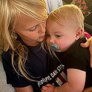Zack joined the competition — help win amazing prizes! children, siblings, baby, toddler, blond_hair, cuddling, kiss, pacifier, portrait, indoors, seated, hug, affection, family, black_shirt, warm_lighting, close_up, car_seat, cozy, candid