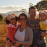 family, outdoor, children, parents, smiling, nature, mountains, sunlight, curly_hair, headband, casual_clothing, grass, trees, sky, portrait, togetherness, happy, love, people, daytime