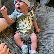 Elijah joined the competition — help win amazing prizes! baby, infant, nike, clothing, hat, socks, blanket, hand, person, indoor, cute, expression, sitting, soft_texture, apparel, footwear, newborn, child, young, cozy