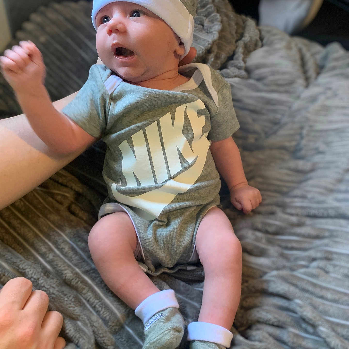 Elijah joined the competition — help win amazing prizes! apparel, baby, blanket, child, clothing, cozy, cute, expression, footwear, hand, hat, indoor, infant, newborn, nike, person, sitting, socks, soft_texture, young