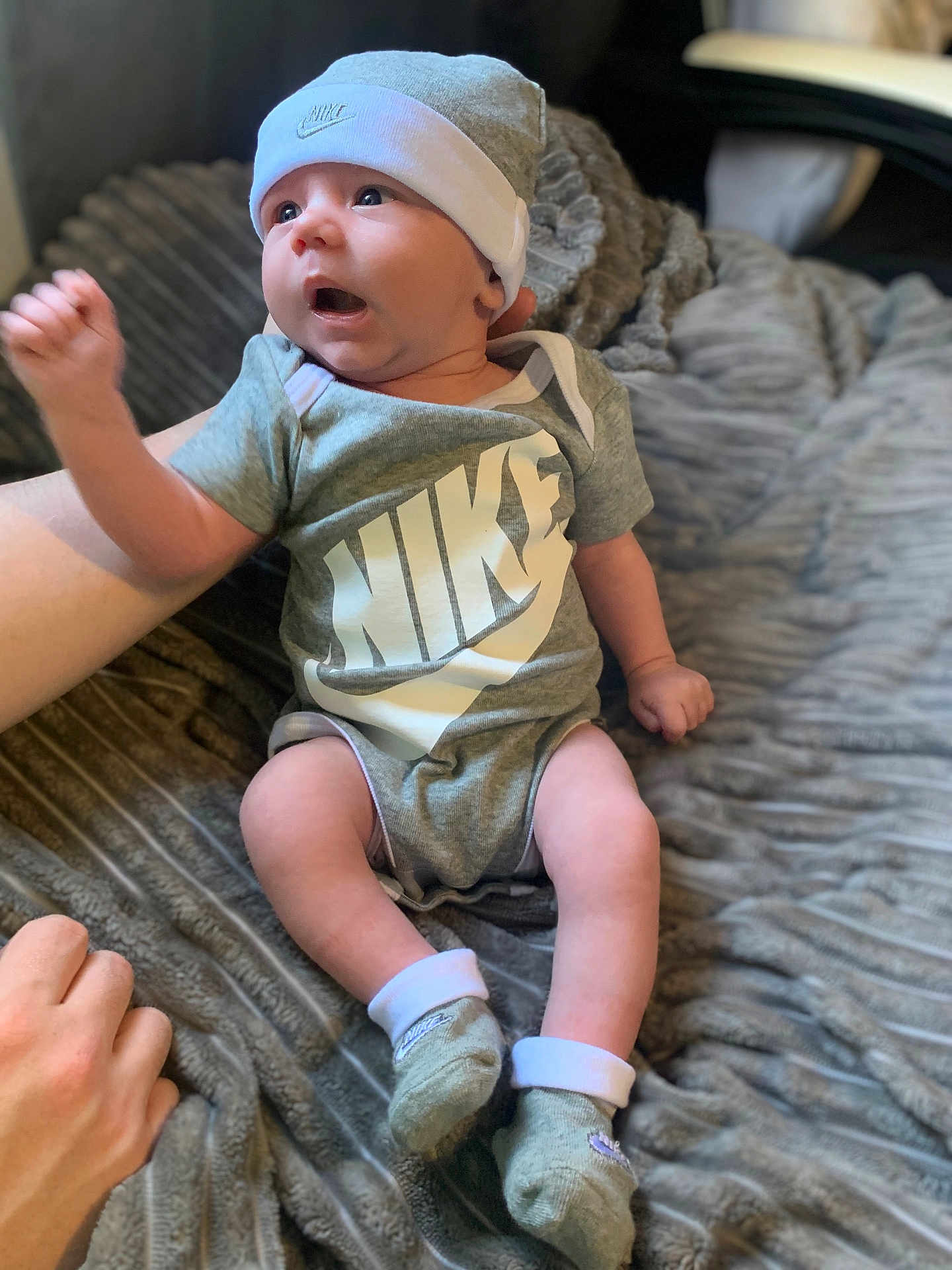 Elijah joined the competition — help win amazing prizes! baby, infant, nike, clothing, hat, socks, blanket, hand, person, indoor, cute, expression, sitting, soft_texture, apparel, footwear, newborn, child, young, cozy