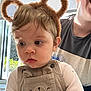 Cooper joined the competition — help win amazing prizes! adult, baby, bear_ears, child, clothing, curly_hair, cute, expression, face, headband, holding, indoor, long_sleeve_shirt, overalls, person, portrait, smile, sunlight, toddler, window
