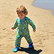 Cooper joined the competition — help win amazing prizes! beach, blue_shoes, child, coast, curly_hair, dinosaur_print, footwear, happy, nature, onesie, outdoor, person, playful, sand, shadow, summer, sunlight, toddler, walking, water