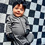 baby, infant, onesie, black_bow, headband, mittens, checkered_blanket, smile, face, blue_eyes, child, cute, lying_down, soft_texture, cozy, portrait, indoor, apparel, baby_clothes, adorable