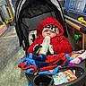 baby, stroller, bottle, milk, red_jacket, beanie, gloves, blanket, cartoon, bus, priority_seat, window, seat, floor, toy, child, person, indoor, cold_weather, transportation