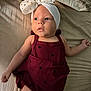 baby, infant, child, bed, blanket, headband, dress, maroon, hearts, clothing, skin, face, arm, leg, laying, indoors, soft_light, cute, portrait, human