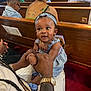 Kai'Loni is registered to the contest to win money with this photo: baby, child, person, woman, glasses, tattoo, watch, headband, dress, pew, church, people, seated, audience, indoor, red_carpet, holding_hands, curious, portrait, casual