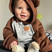 Charles a rejoint le concours — aidez-le/la à gagner de superbes lots ! baby, child, smile, hoodie, brown, gray, cute, face, portrait, indoors, soft_lighting, sitting, clothing, cozy, happy, young_child, footwear, warm, expression, infant