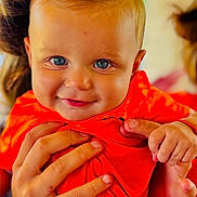 ézio a rejoint le concours — aidez-le/la à gagner de superbes lots ! baby, child, smile, blue_eyes, orange_shirt, hands, portrait, close_up, cute, infant, person, skin, face, expression, holding, bright_colors, happy, young_child, human, background_blur