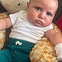 Asher is registered to the contest to win money with this photo: baby, child, plush_toy, giraffe, stuffed_animal, white_shirt, teal_pants, indoor, couch, cute, infant, face, expression, soft_toy, seated, cozy, young, person, portrait, comfort