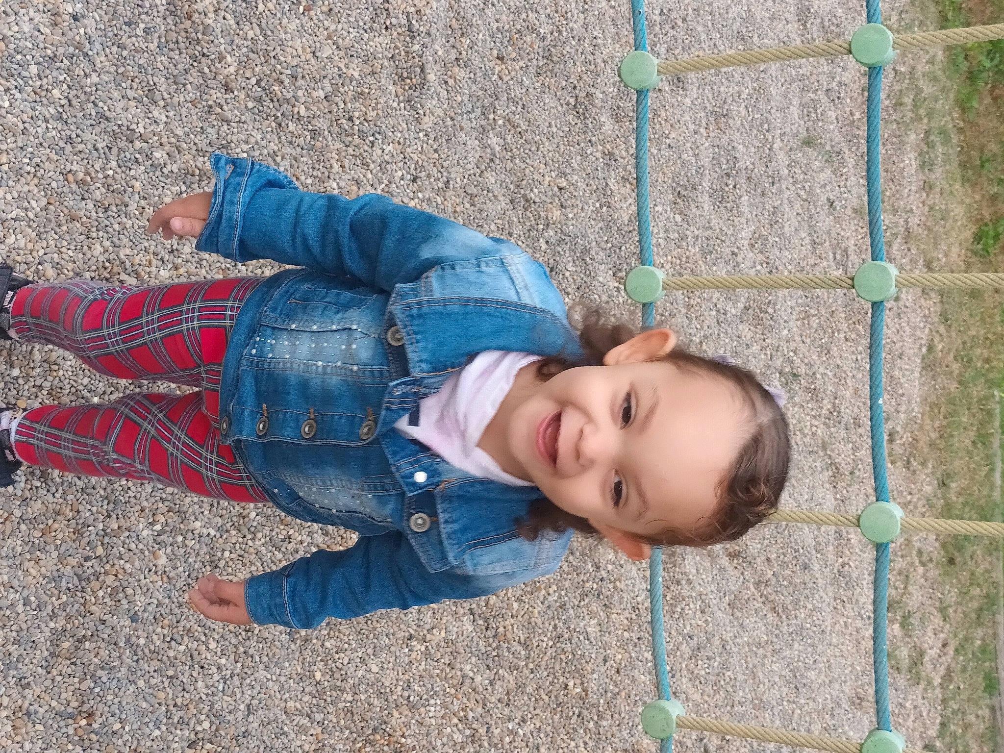 Nélya participe au concours pour gagner de l'argent avec cette photo : baby, baby_toddler_clothing, child, denim, electric_blue, fence, fun, grass, happy, jeans, joy, leisure, mesh, pattern, person, play, public_space, sitting, smile, toddler
