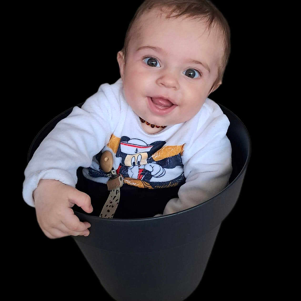 Liam participe au concours pour gagner de l'argent avec cette photo : baby, black_background, bucket, child, clothing, cute, face, happy, head, indoor, infant, joyful, mickey_mouse, pacifier_clip, person, portrait, sitting, small_hand, smiling, sweater