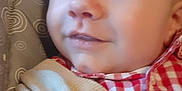 Charly participe au concours pour gagner de l'argent avec cette photo : baby, child, smile, face, clothing, cardigan, red_checkered_shirt, patterned_cushion, close_up, indoor, cute, portrait, young_child, infant, head, eyes, skin, happy, baby_fashion, seated