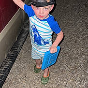 Judsen is registered to the contest to win money with this photo: child, boy, cap, hat, blue_shirt, striped_shirt, shark_graphic, green_slippers, dinosaur_slippers, tablet, vehicle, red_vehicle, night, flash_photo, gravel, outdoor, standing, toy, play, casual_clothing