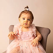 Luna a rejoint le concours — aidez-le/la à gagner de superbes lots ! toddler, child, dress, pink, chair, portrait, baby, cute, sitting, indoors, person, young_child, curly_hair, scrunchie, blue_eyes, soft_lighting, fabric, lace, background, smile