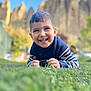 child, boy, smiling, grass, outdoor, sweater, blue_sky, nature, rocks, portrait, happy, casual_clothing, daylight, young, cute, head, face, person, playing, leisure