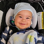 Darius joined the competition — help win amazing prizes! baby, smiling, child, hat, blanket, car_seat, clothing, cute, happy, infant, face, person, warm, cozy, striped, black, white, blue, sitting, indoors