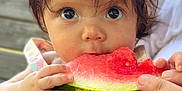 Valentina is registered to the contest to win money with this photo: baby, child, watermelon, fruit, eating, hands, closeup, face, cute, summer, outdoor, food, skin, person, expression, natural_light, hair, holding, infant, snack