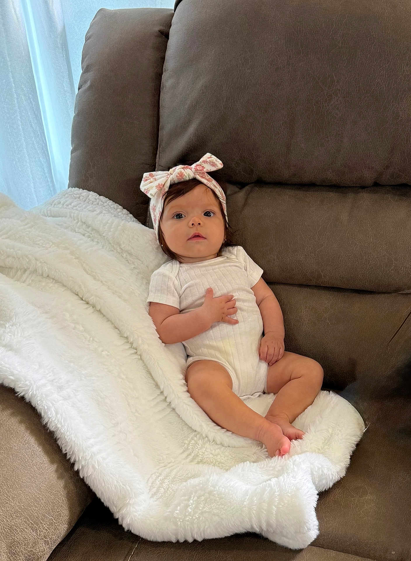 Valentina joined the competition — help win amazing prizes! baby, infant, headband, blanket, couch, brown_couch, white_blanket, baby_clothing, indoors, child, face, person, cute, relaxed, sitting, young_child, soft_texture, cozy, portrait, looking