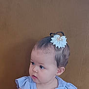 Neyla a rejoint le concours — aidez-le/la à gagner de superbes lots ! baby, blue_top, child, clothing, couch, curious, cute, floor, floral_skirt, flower_hair_clip, hair_accessory, indoor, looking_away, person, portrait, ruffled_sleeves, sitting, toddler, wooden_floor, young_child