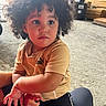 Joandry is registered to the contest to win money with this photo: child, toddler, curly_hair, puma, sporty_clothing, black_pants, yellow_shirt, bracelet, indoor, floor, wooden_background, person, young_child, cute, sitting, casual, expression, portrait, fashion, relaxed