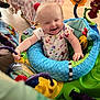 Keira is registered to the contest to win money with this photo: baby, child, activity_center, toys, indoor, colorful, smile, blurred_face, clothing, plastic, play, furniture, blanket, wood_floor, happy, infant, seat, hand, head, expression