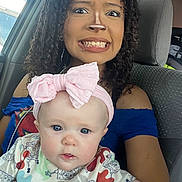 Keira is registered to the contest to win money with this photo: woman, baby, car, headband, curly_hair, facial_piercing, blue_shirt, spongebob, seat, seatbelt, expression, cute, child, person, indoor, portrait, holding, funny_face, clothing, accessory