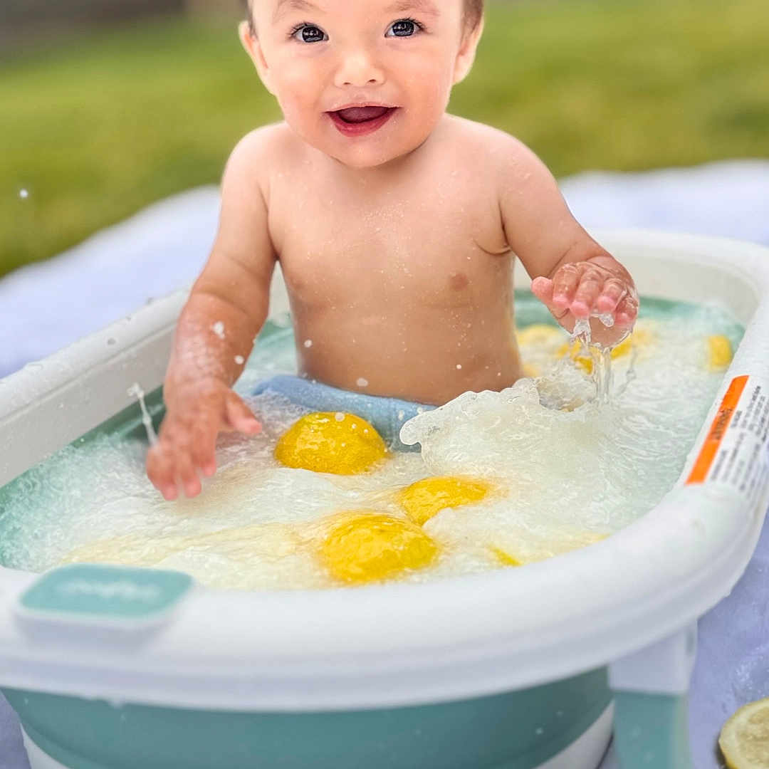 Ostap is registered to the contest to win money with this photo: baby, bathtub, child, face, fence, fun, grass, happy, head, lemon, outdoor, person, play, skin, smiling, splashing, summer, sunlight, toddler, water