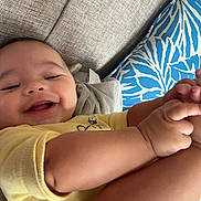 Braylen joined the competition — help win amazing prizes! baby, child, close_up, couch, cushion, family_photo, hands, happy, home, indoor, infant, legs, lying_down, patterned_pillow, portrait, relaxed, sitting, smiling, sofa, yellow_clothing