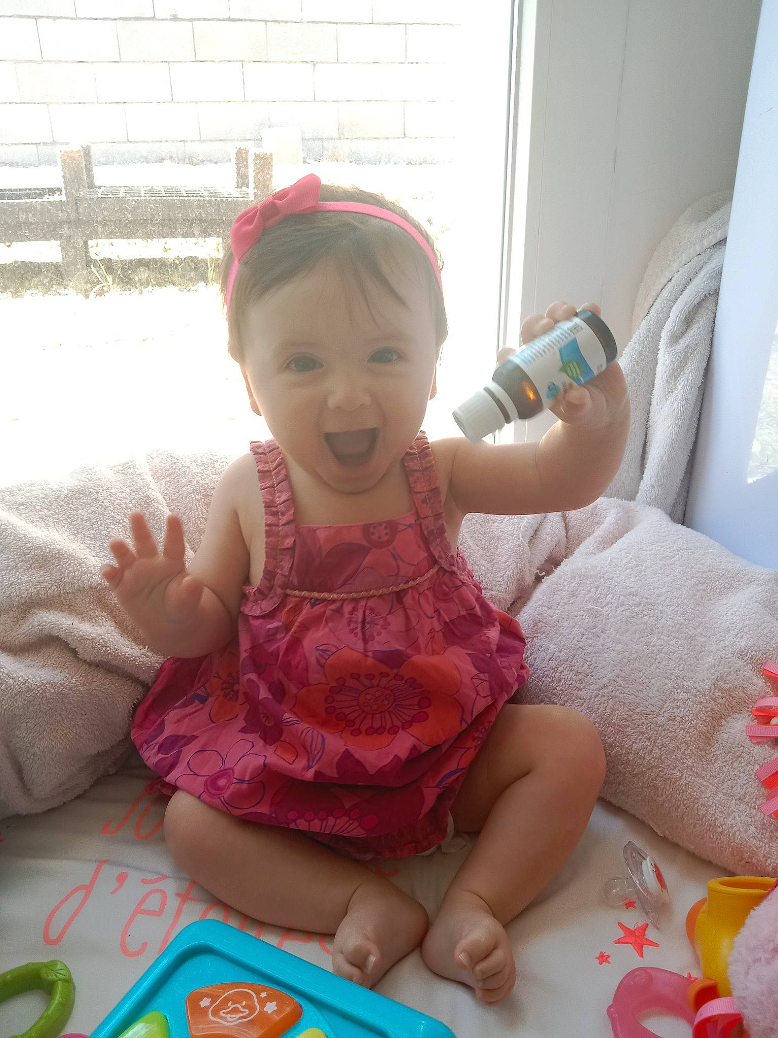 Noélia a rejoint le concours — aidez-le/la à gagner de superbes lots ! baby, baby_toddler_clothing, child, comfort, dress, finger, fun, happy, head, magenta, people, person, pink, room, sitting, skin, smile, sock, thumb, toddler