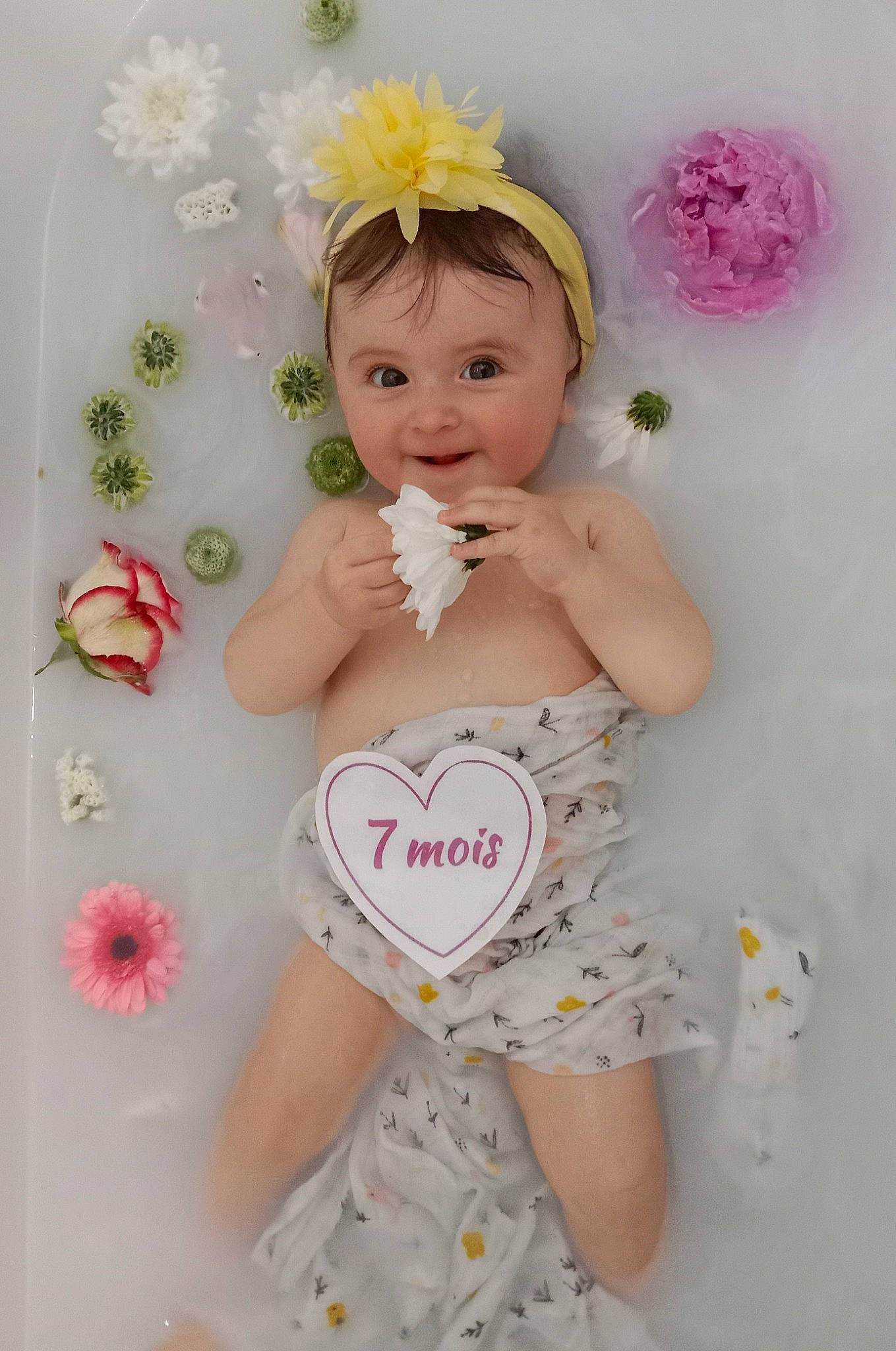 Noélia a rejoint le concours — aidez-le/la à gagner de superbes lots ! arm, baby, baby_toddler_clothing, brown_hair, cheek, chest, diaper, flower, happy, head, headpiece, joy, peach, person, petal, pink, skin, stomach, textile, thigh
