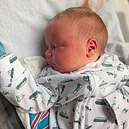 Kaleb is registered to the contest to win money with this photo: newborn, baby, sleeping, infant, portrait, face, head, closed_eyes, blanket, swaddled, onesie, pajamas, clothing, bed, bedding, indoors, cozy, peaceful, vehicle_pattern, photography