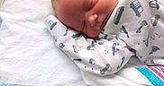 Kaleb is registered to the contest to win money with this photo: newborn, baby, sleeping, infant, face, portrait, pacifier, swaddled, blanket, hospital, bedding, onesie, clothing, vehicle_pattern, peaceful, resting, indoors, close_up, head, child