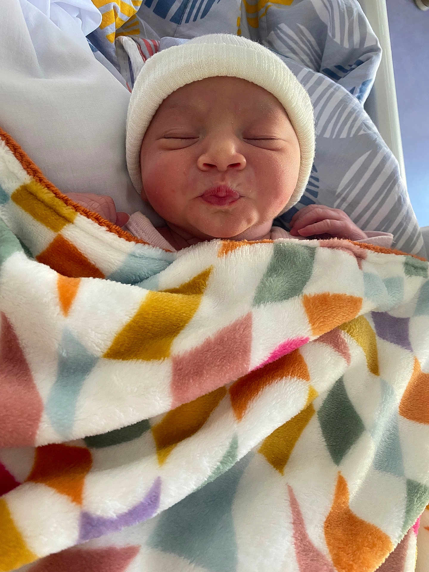 Louise a rejoint le concours — aidez-le/la à gagner de superbes lots ! baby, newborn, blanket, hat, bed, sleeping, puckered_lips, infant, colorful, geometric_pattern, cozy, cute, resting, closeup, soft, child, person, warm, indoors, peaceful